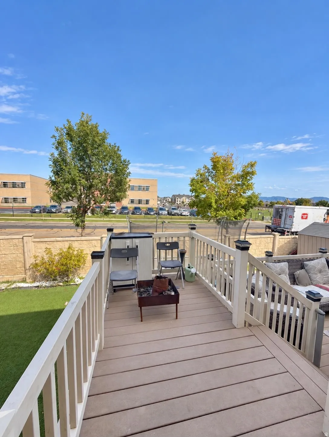 Composite deck with light-colored railings, artificial turf yard, and a stone-finish privacy wall