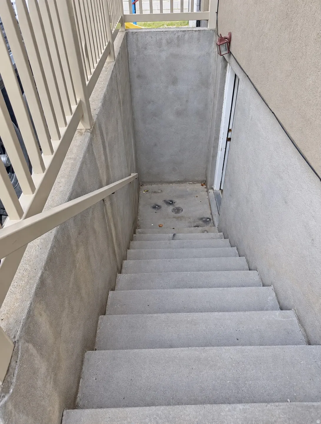 Concrete stairwell with a metal handrail and a light-colored exterior wall