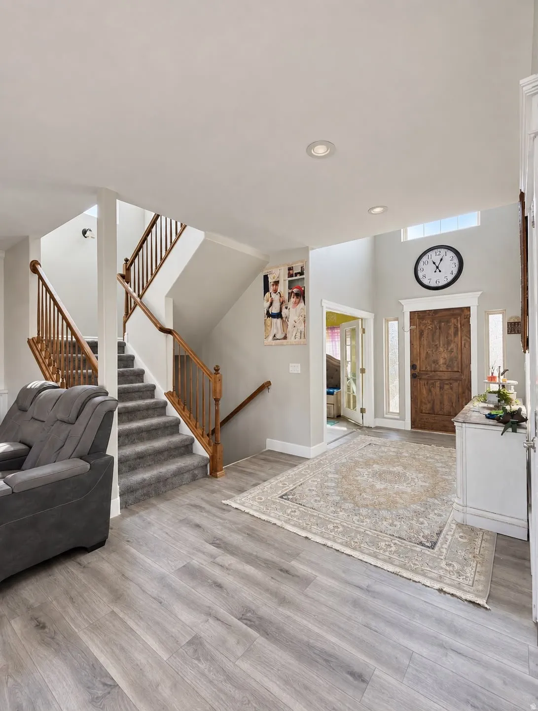 Two-story foyer with wood-finish flooring, recessed lighting, and a wooden entry door