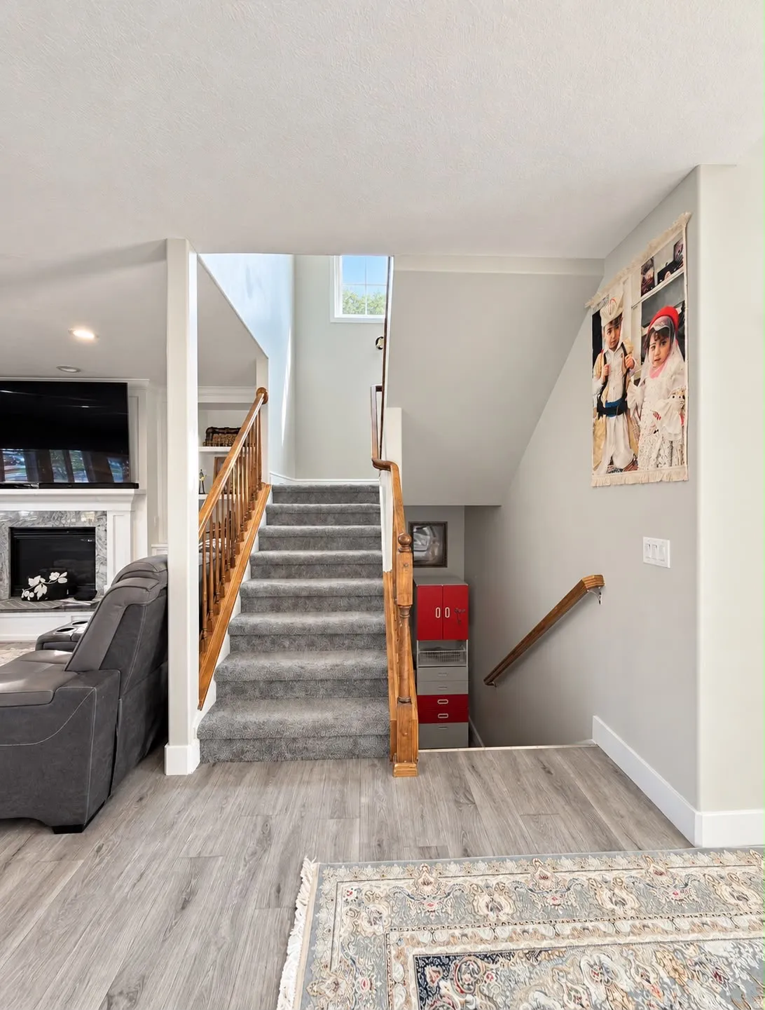 Carpeted staircase with wood-finish handrails, wood-finish flooring, and a window