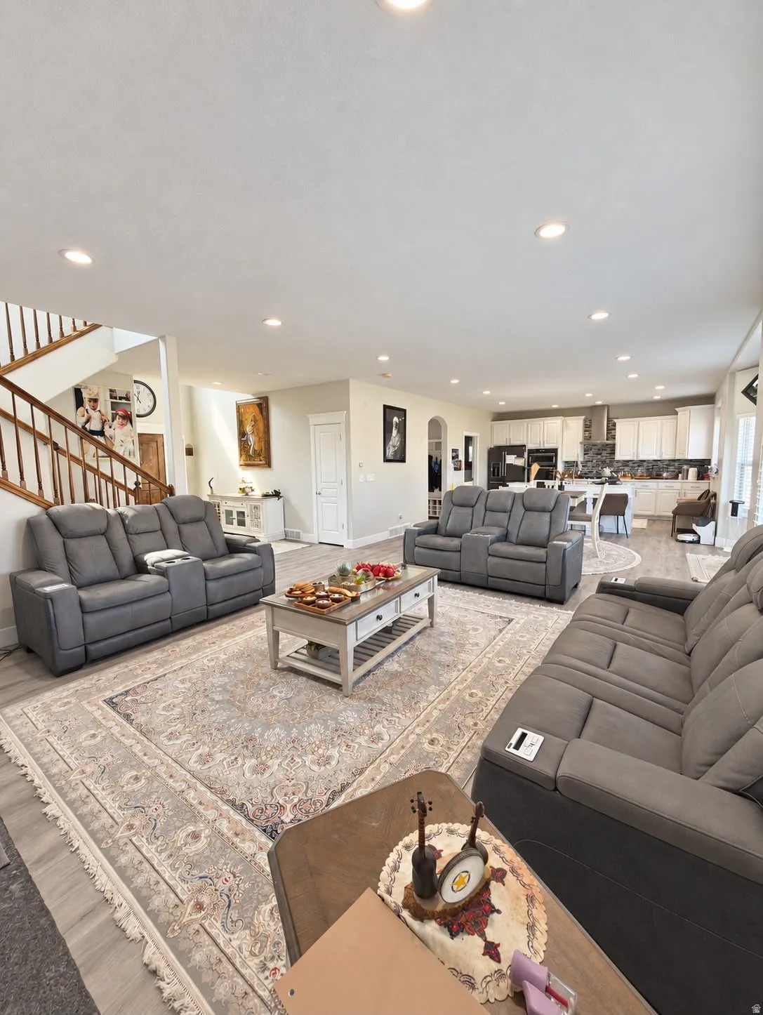 Open-concept living area featuring wood-finish flooring, recessed lighting, and a staircase with wood railings
