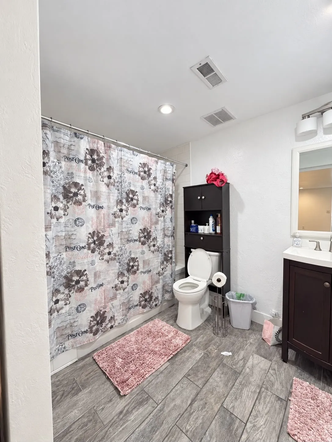 Bathroom featuring wood-finish tile flooring, a shower-tub combination, and a single-sink vanity with storage
