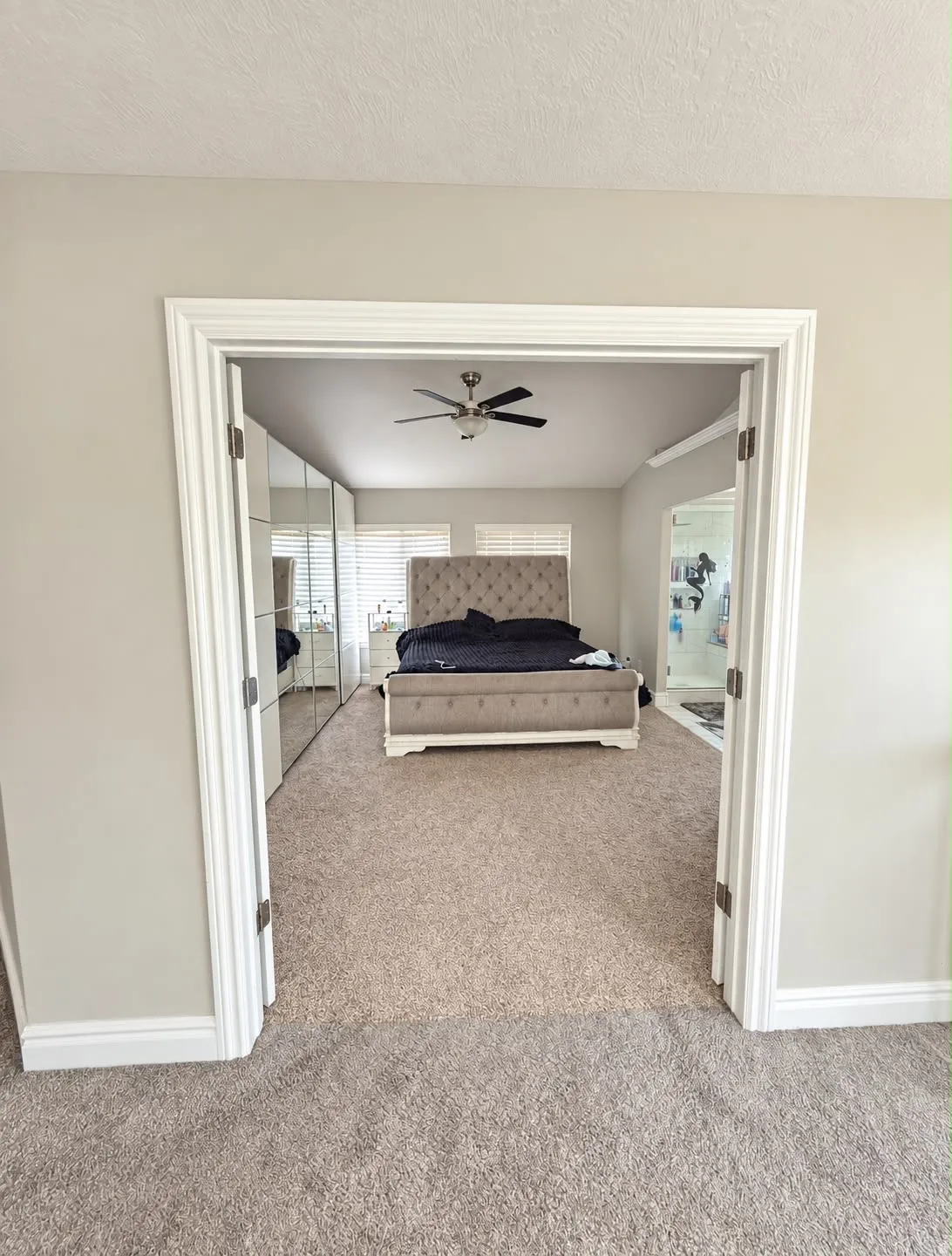 Neutral-toned carpeting, white trim, and a ceiling fan with integrated lighting
