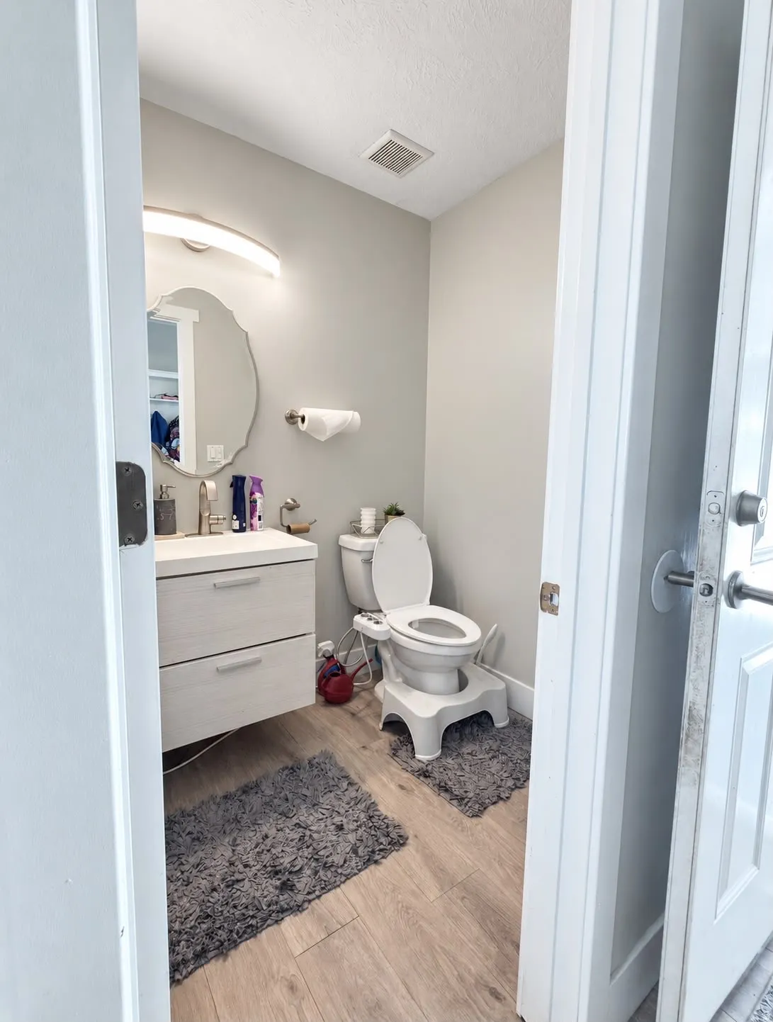 Floating vanity with dual drawers, wood-finish flooring, and a decorative mirror