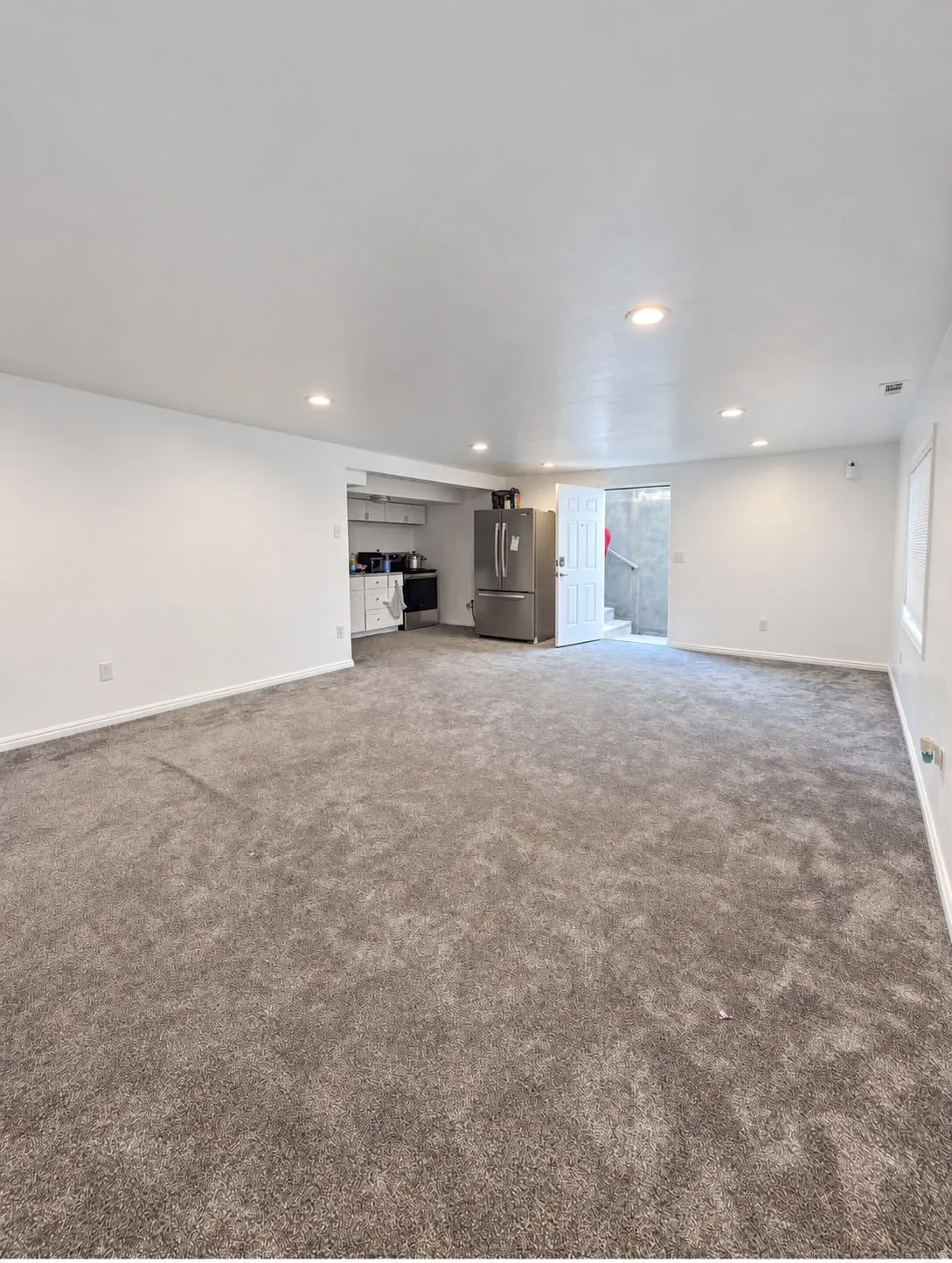 Expansive room with neutral carpeting, recessed ceiling lighting, and crisp white walls