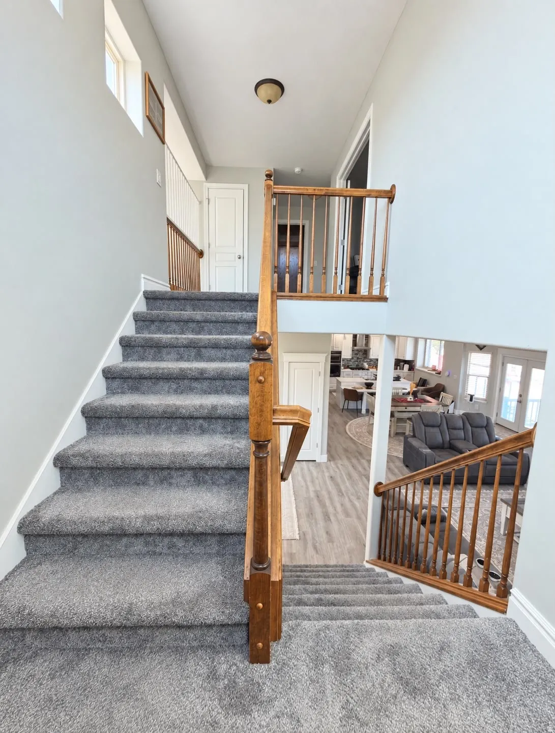 Carpeted staircase with wood railing, leading to a second-story landing with a light fixture