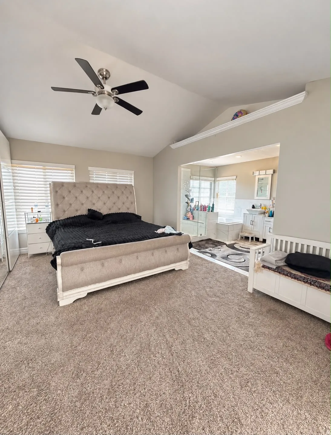 Vaulted ceiling with a ceiling fan, carpeted flooring, and an open doorway to an adjoining room