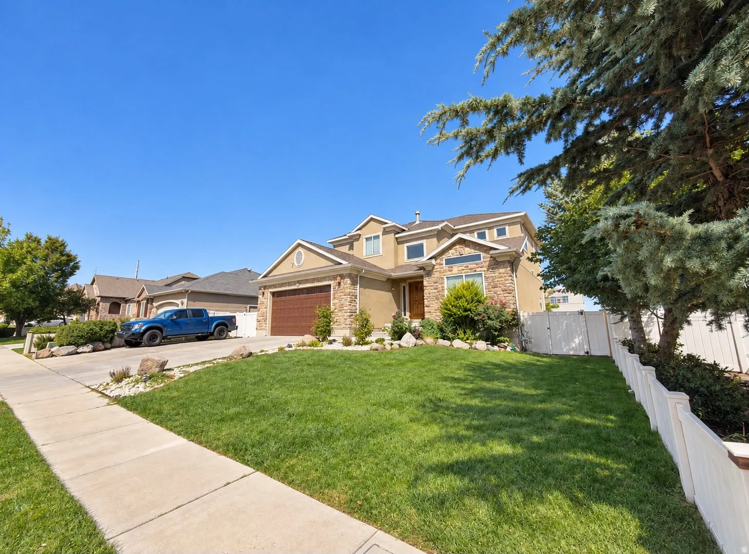 Two-story residence featuring a stone and stucco exterior, an attached two-car garage, and a concrete driveway