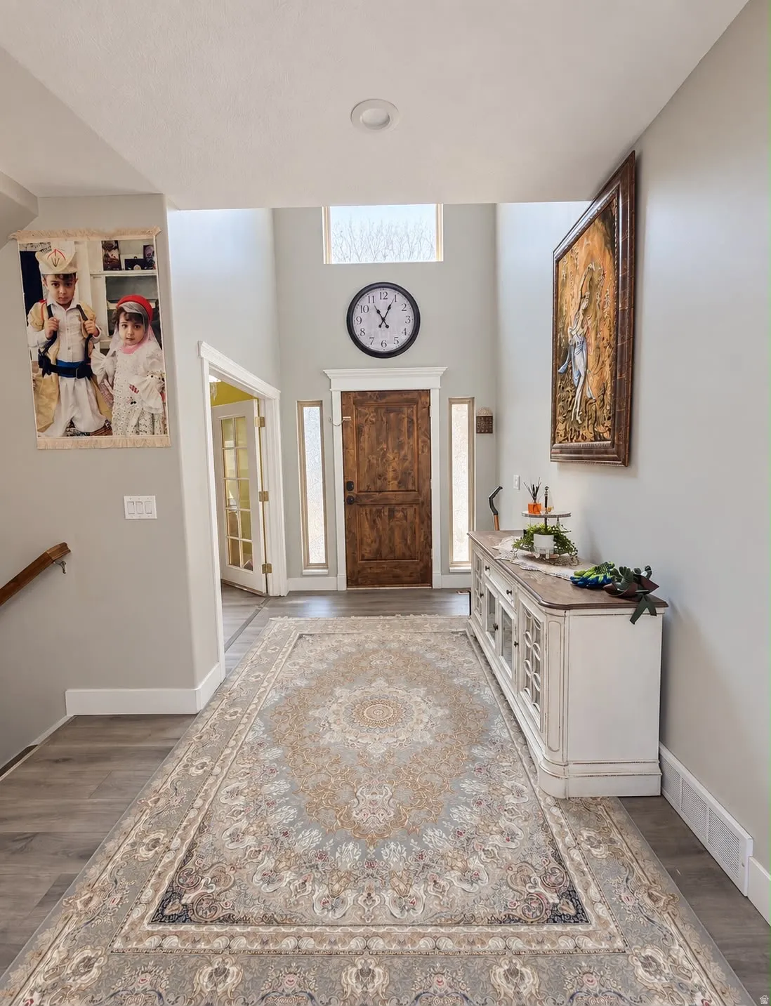 Two-story foyer featuring wood-finish flooring, a wood entry door, and transom window