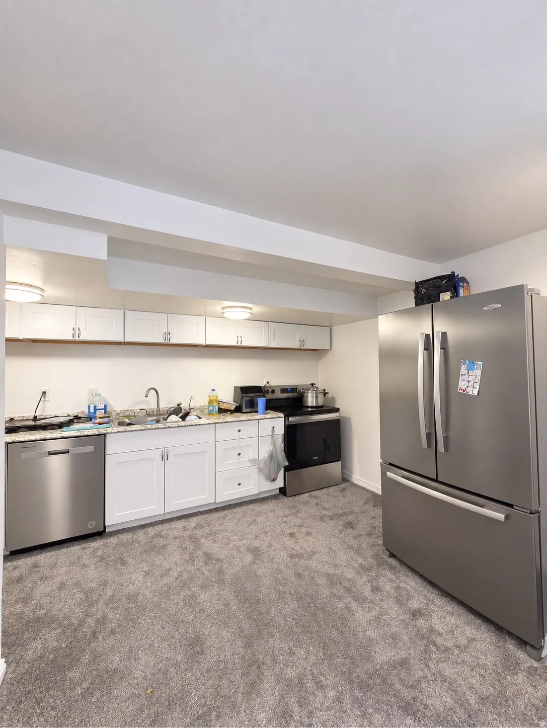 Kitchenette with stainless steel appliances, white cabinetry, and granite-style countertops