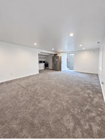 Expansive room with neutral carpeting, recessed ceiling lighting, and crisp white walls