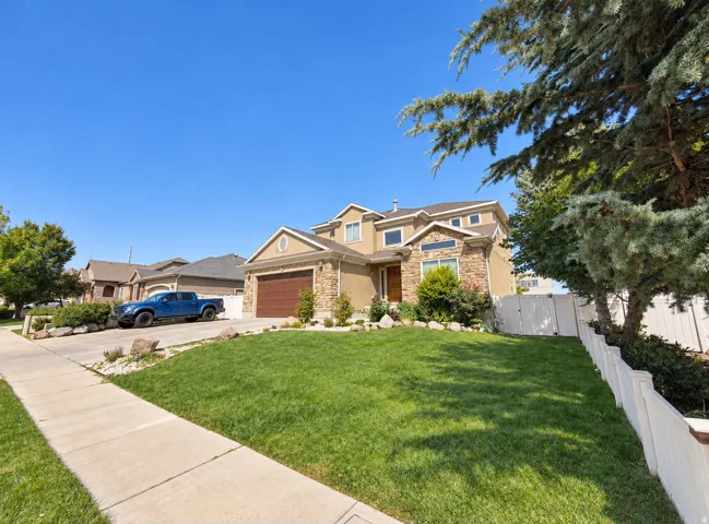 Two-story residence featuring a stone and stucco exterior, an attached two-car garage, and a concrete driveway