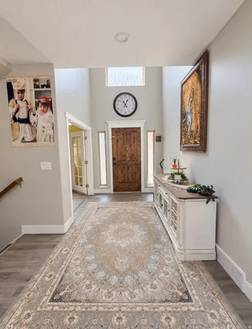 Two-story foyer featuring wood-finish flooring, a wood entry door, and transom window