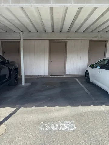 Covered parking space with a corrugated metal ceiling and concrete flooring