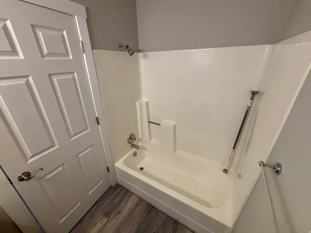 Fiberglass tub/shower combination with chrome fixtures, and wood-finish flooring