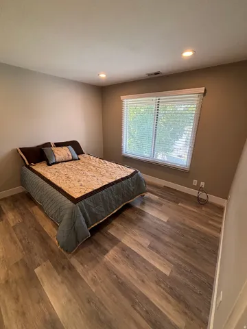 Recessed ceiling lighting, wood-finish flooring, and a large window with white blinds
