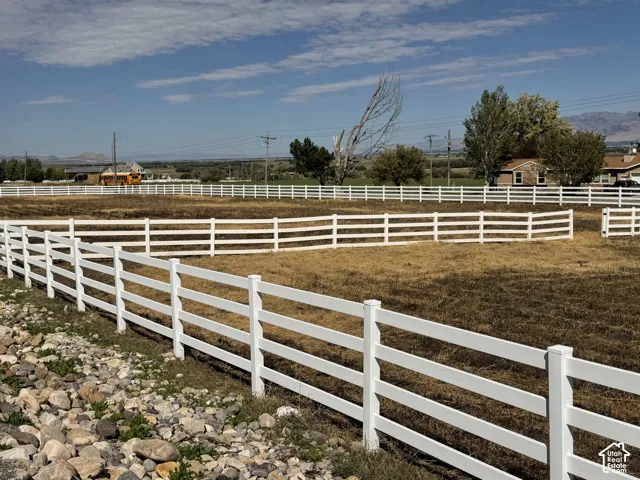 Extensive property featuring multiple white fences, a large open field, and distant mountains