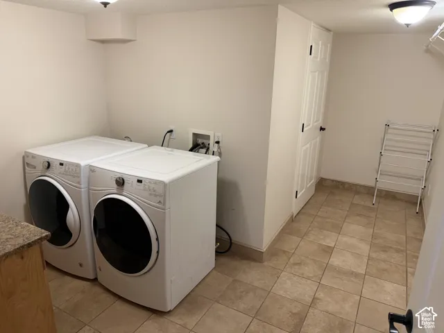 Tile flooring with a light-toned finish, white walls, and a built-in laundry appliance hookup