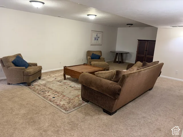 Expansive carpeted room with neutral wall tones and recessed lighting