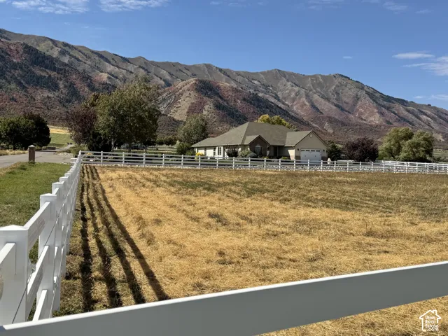 Ranch-style residence featuring an attached garage, white fencing, and paved driveway. Stunning mountain backdrop and Valley views!