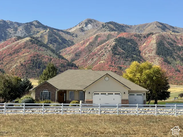 Ranch-style exterior with brick and siding facade, attached three-car garage, and a white rail fence