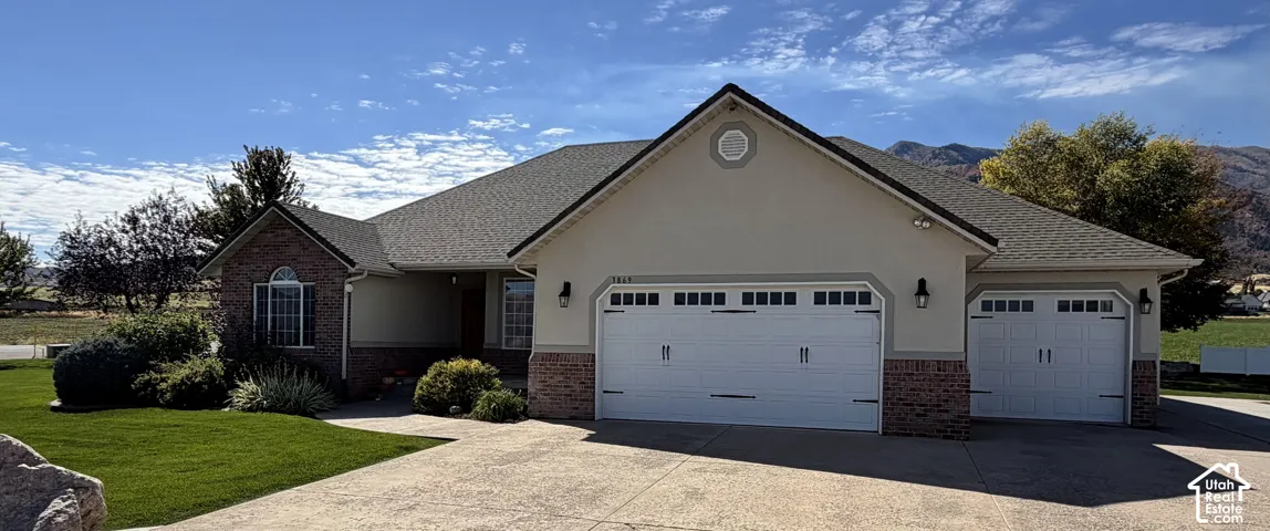 Spacious home featuring a multi-car garage, brick and stucco exterior, arched windows, and a concrete driveway