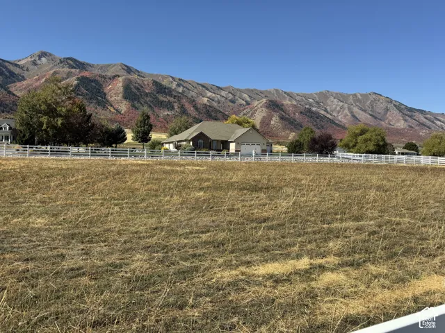 Expansive lot featuring a white fence and distant mountain backdrop