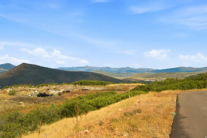 Expansive natural terrain featuring distant mountains, lush green foliage, and a clear blue sky