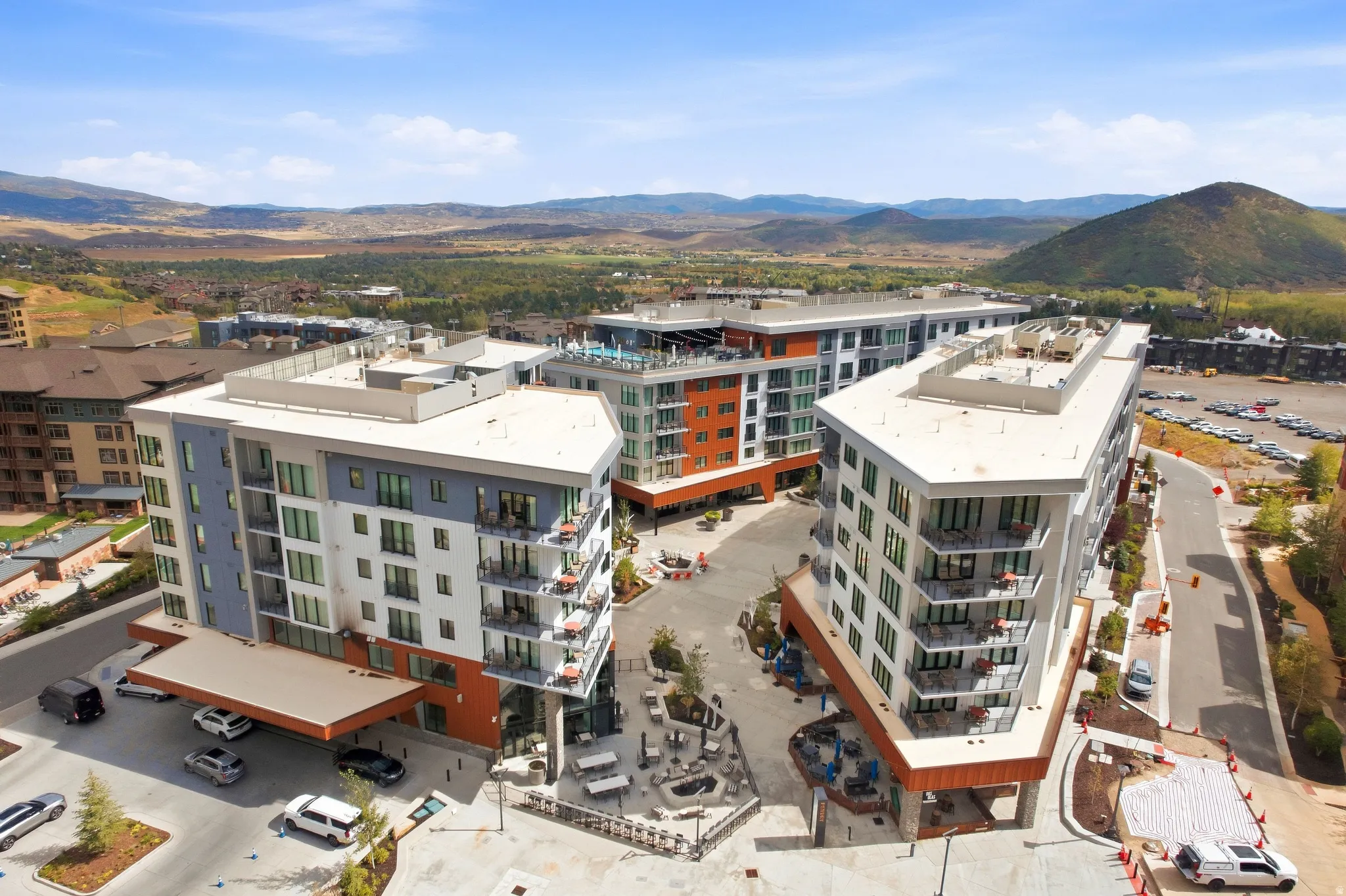 Modern multi-story buildings featuring balconies, a rooftop amenity space, and a covered entry