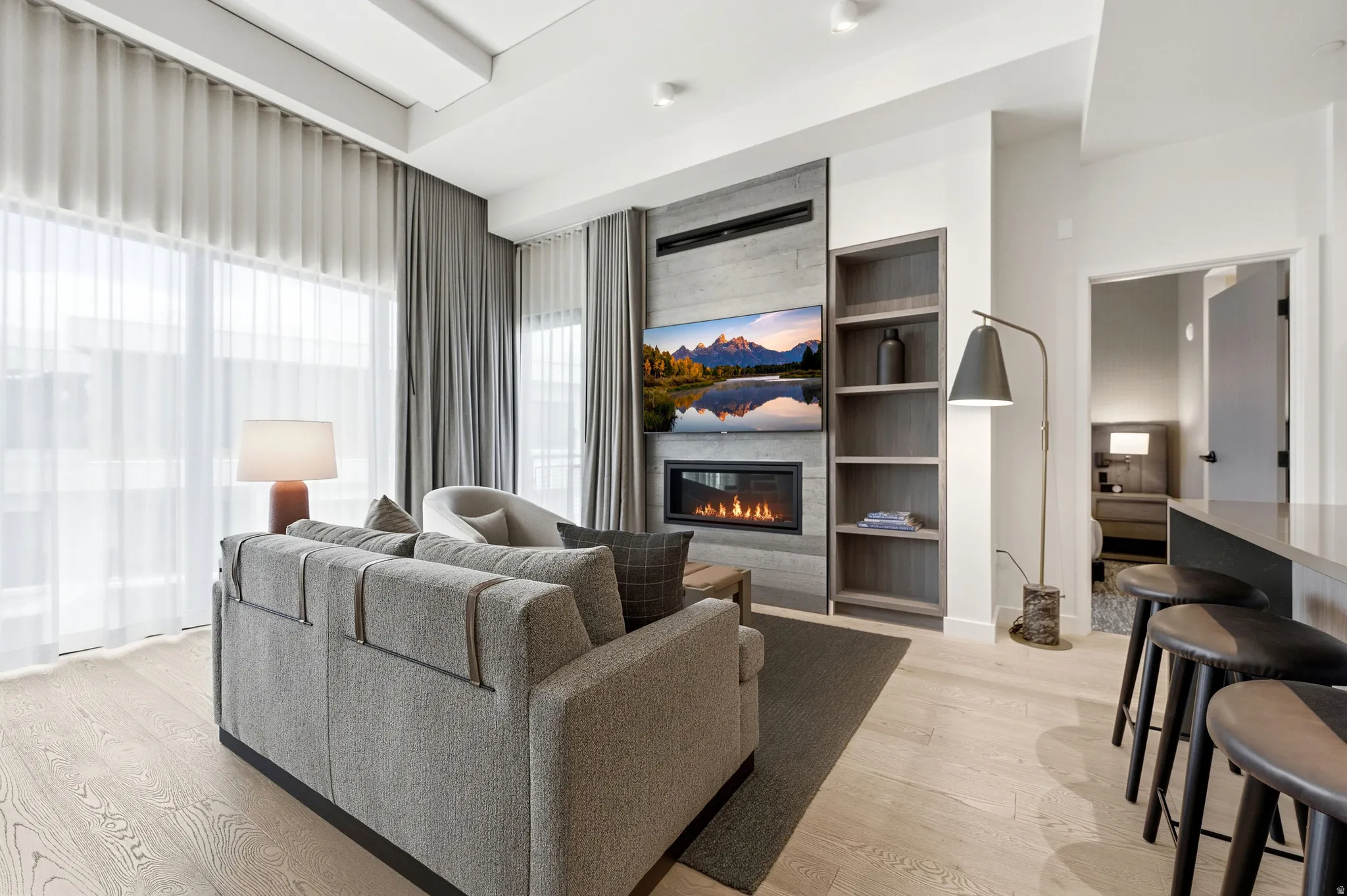 Integrated media wall with an electric fireplace, built-in shelving, and light wood-finish flooring