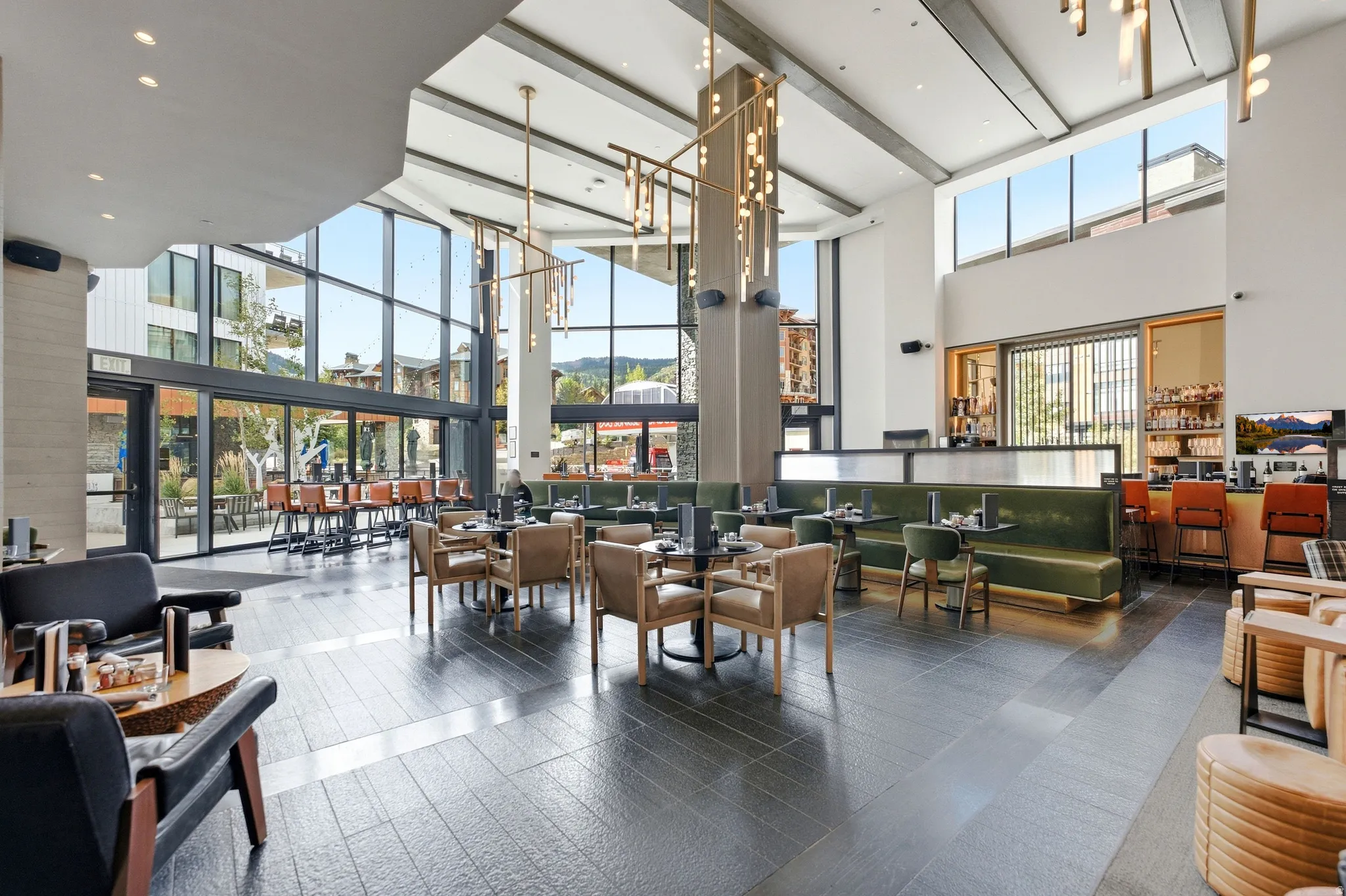 Expansive open-concept space featuring a high vaulted ceiling, full-height windows, a built-in bar area, and dark tile flooring