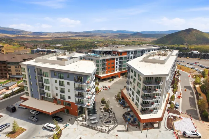 Modern multi-story buildings featuring balconies, a rooftop amenity space, and a covered entry