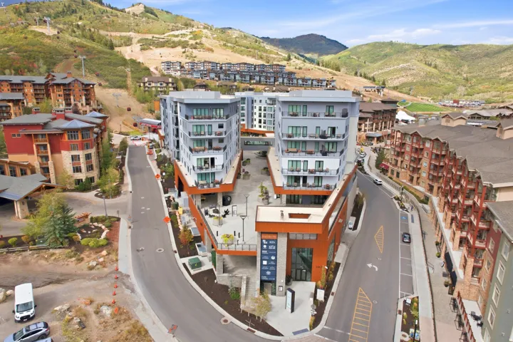 Modern multi-story buildings with balconies, surrounded by mountainous terrain