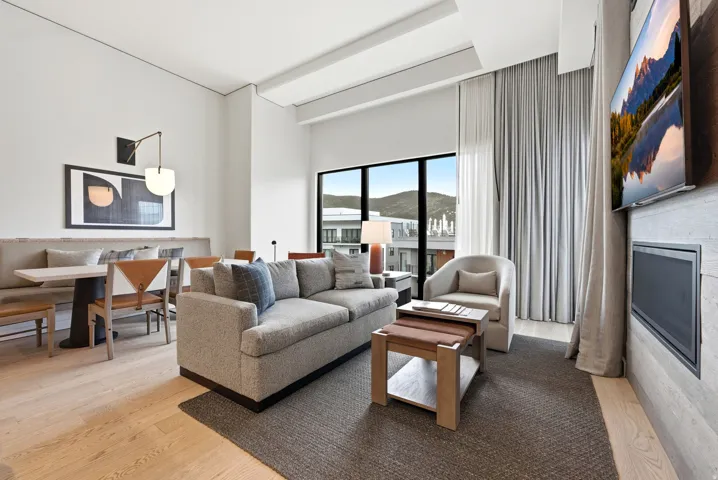 Open-concept living area with light wood-finish flooring, a contemporary fireplace, and a large window