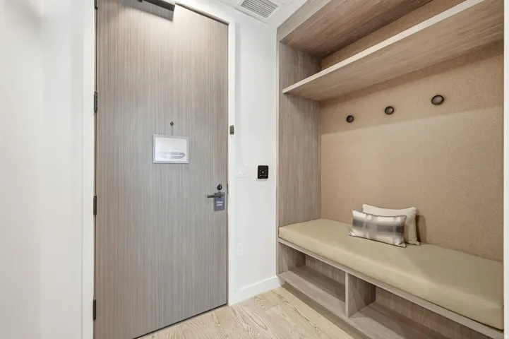 Entryway featuring wood-finish flooring, built-in shelving, integrated bench seating, and wall-mounted hooks