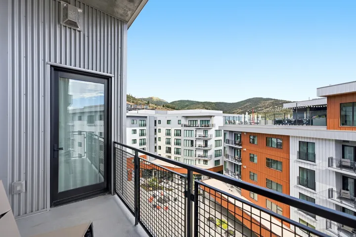 Balcony with dark metal railing, corrugated metal siding, and a full-light door