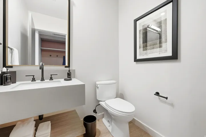 Floating vanity with integrated basin, matte black fixtures, and wood-finish flooring