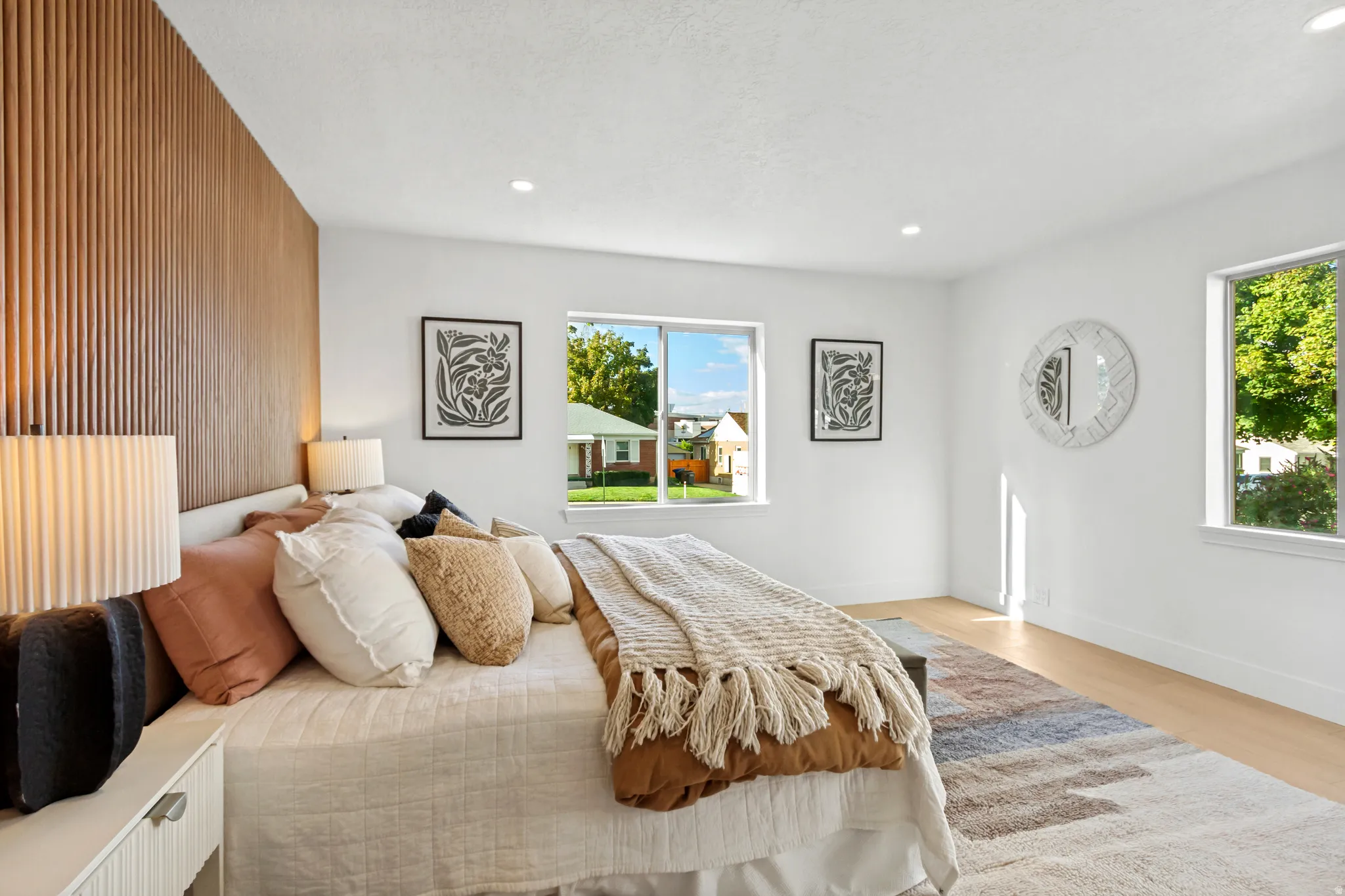 Wood-slat accent wall, recessed lighting, multiple windows, wood-finish flooring