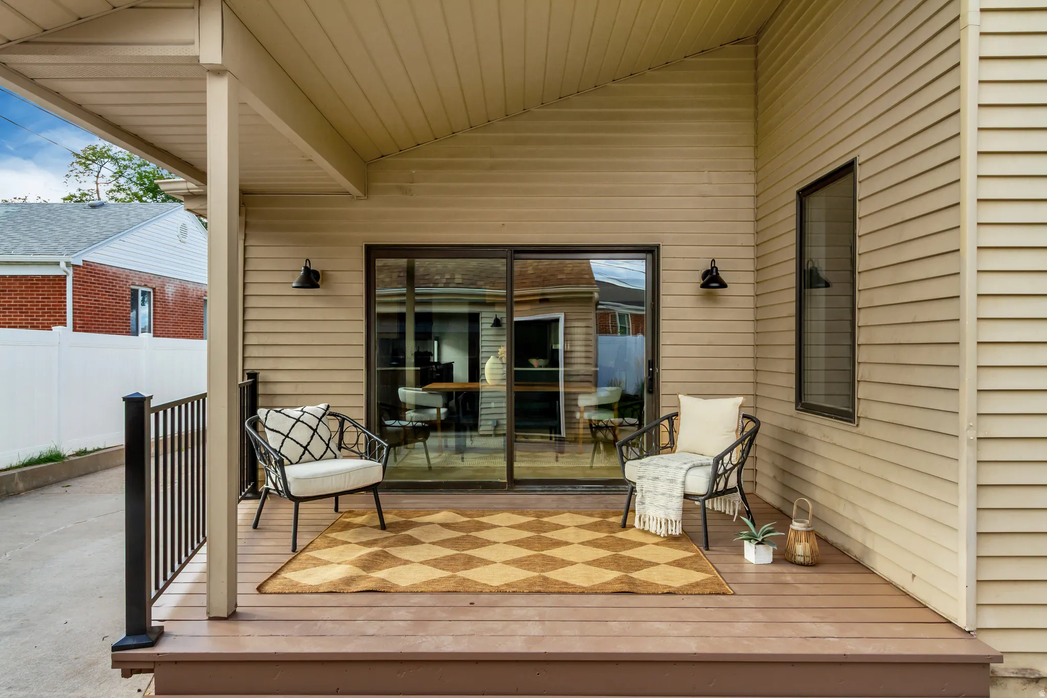 Covered outdoor deck with composite decking, black metal railing, and attached exterior lighting