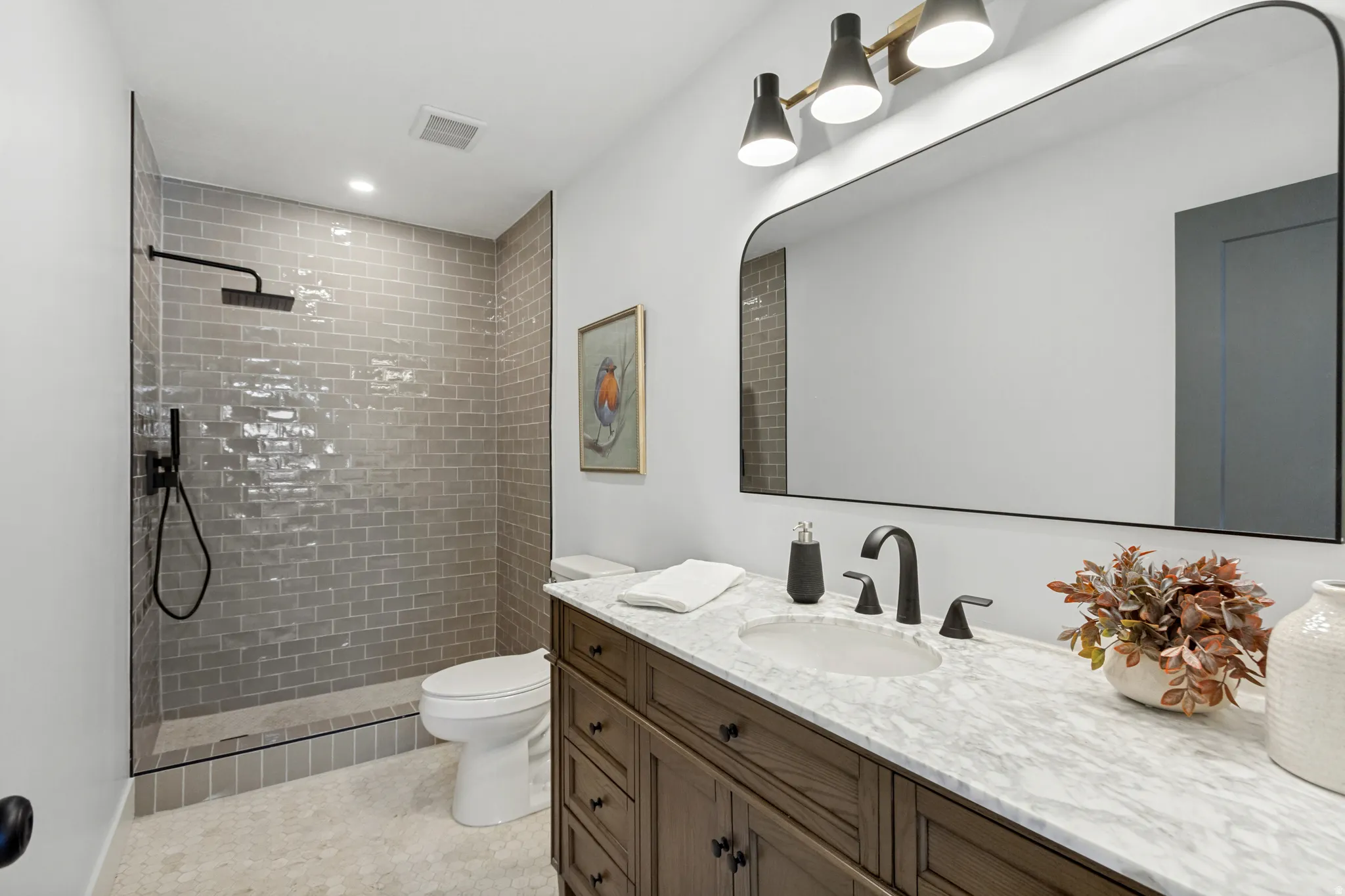 Walk-in shower with gray subway tile surround and black fixtures