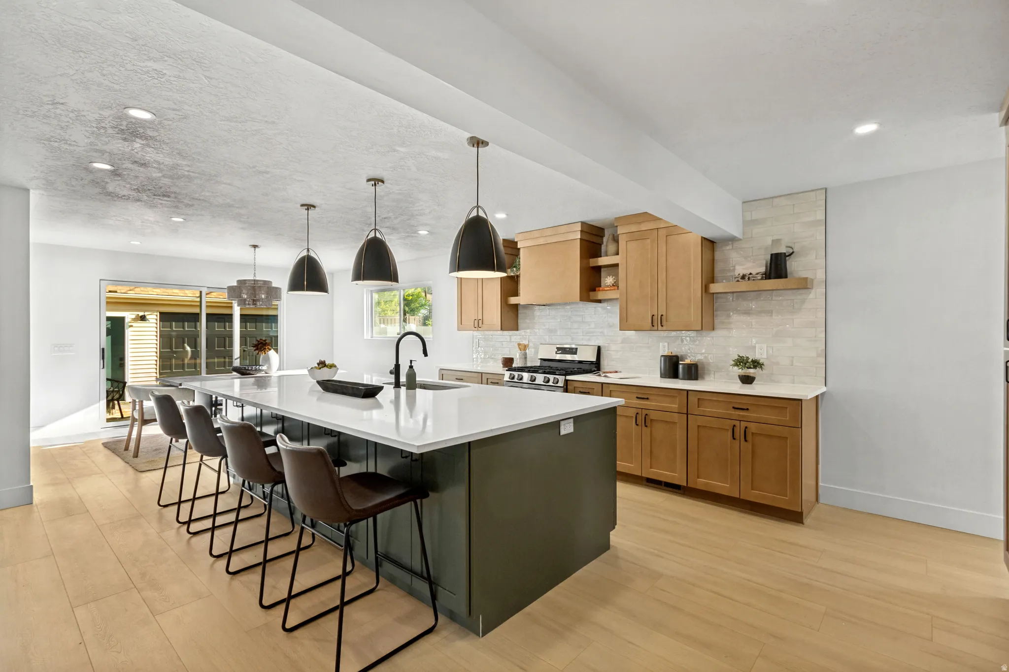 Central kitchen island with a white countertop and dark base, featuring pendant lighting