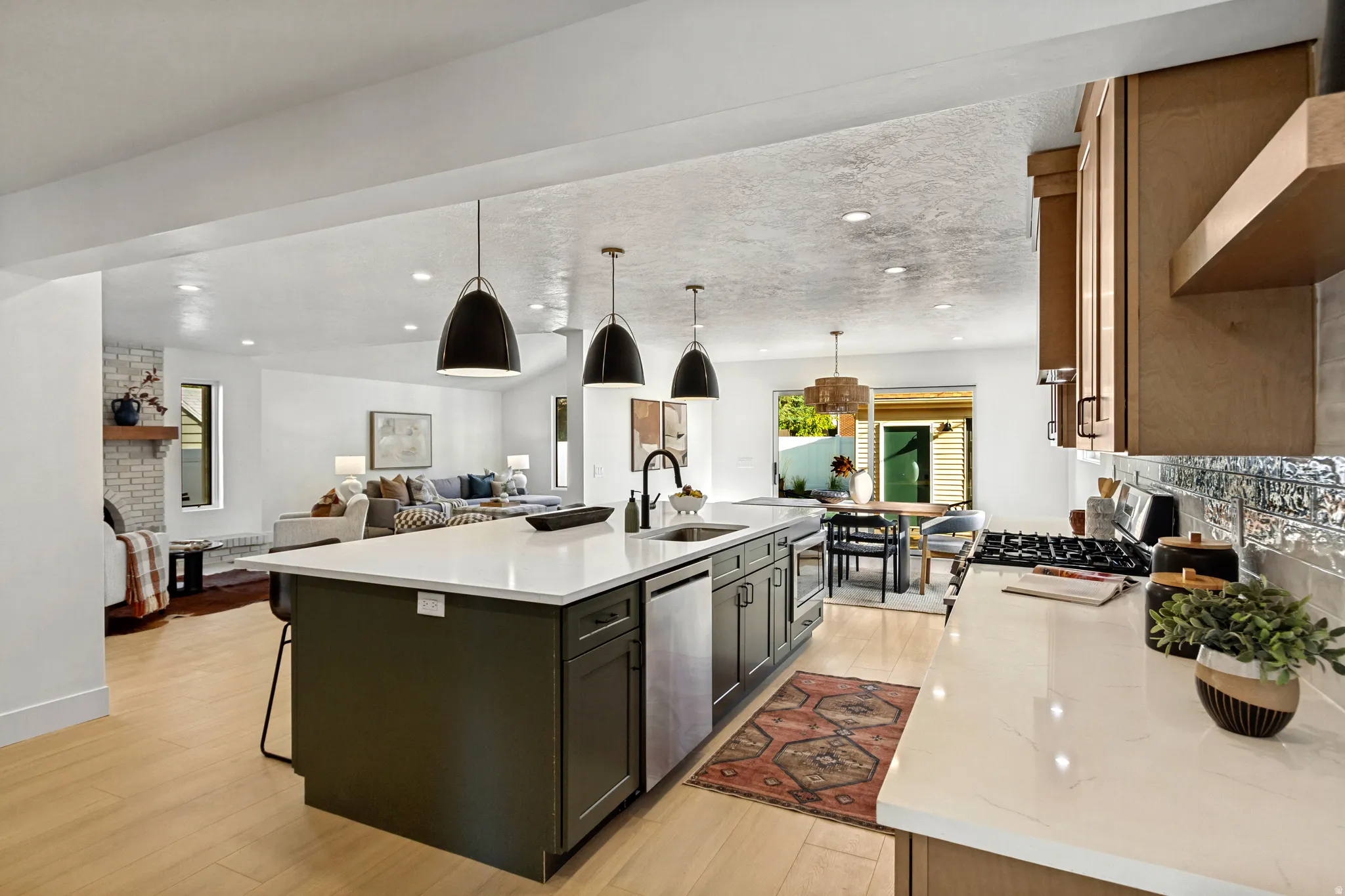 Spacious kitchen featuring a central island, stainless steel appliances, light wood-finish flooring, and light-toned countertops