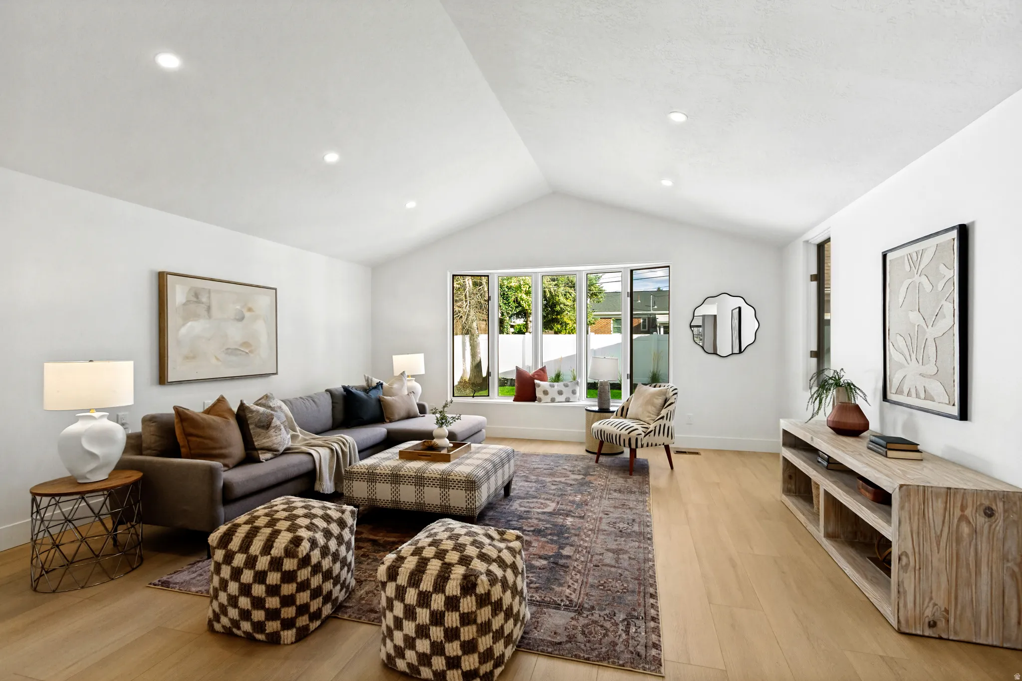 Vaulted ceiling, recessed lighting, expansive window bench, light wood-finish flooring, and white walls