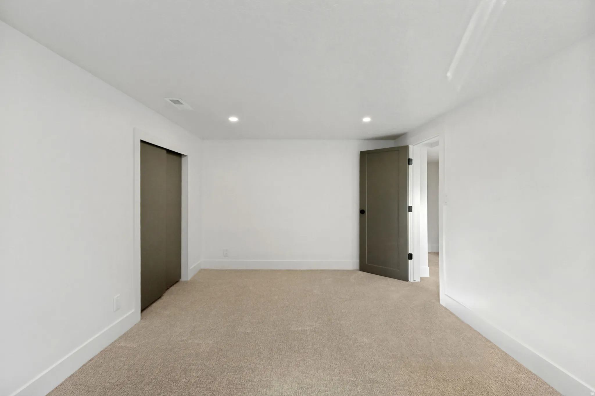 Plush carpeting, recessed lighting, and white walls with contrasting trim