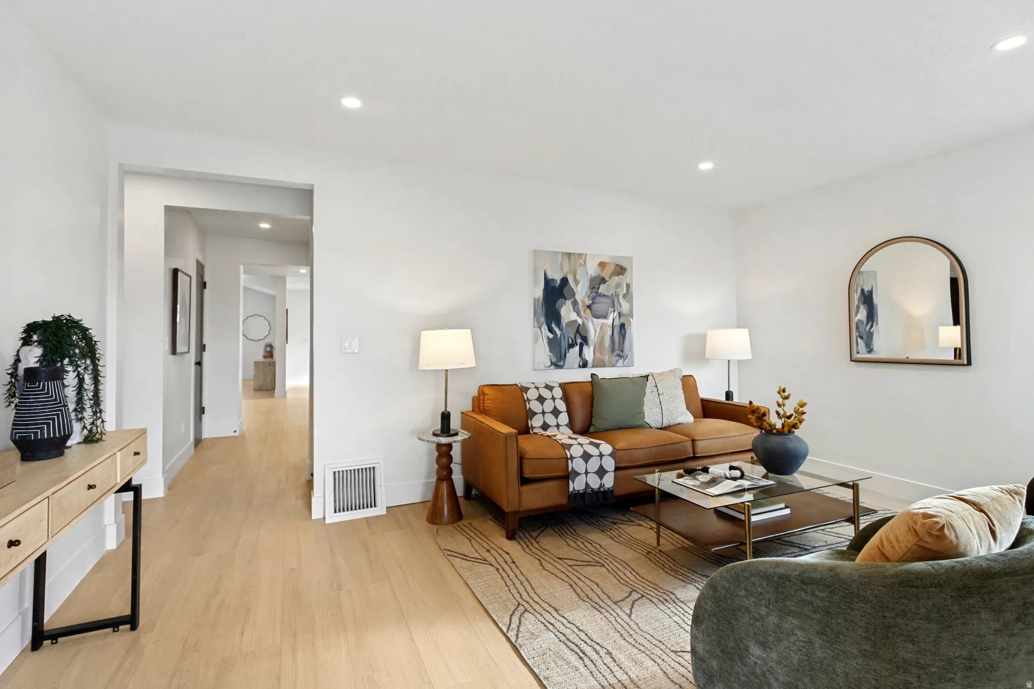 Recessed ceiling lighting, light wood-finish flooring, white walls, and a hallway entry