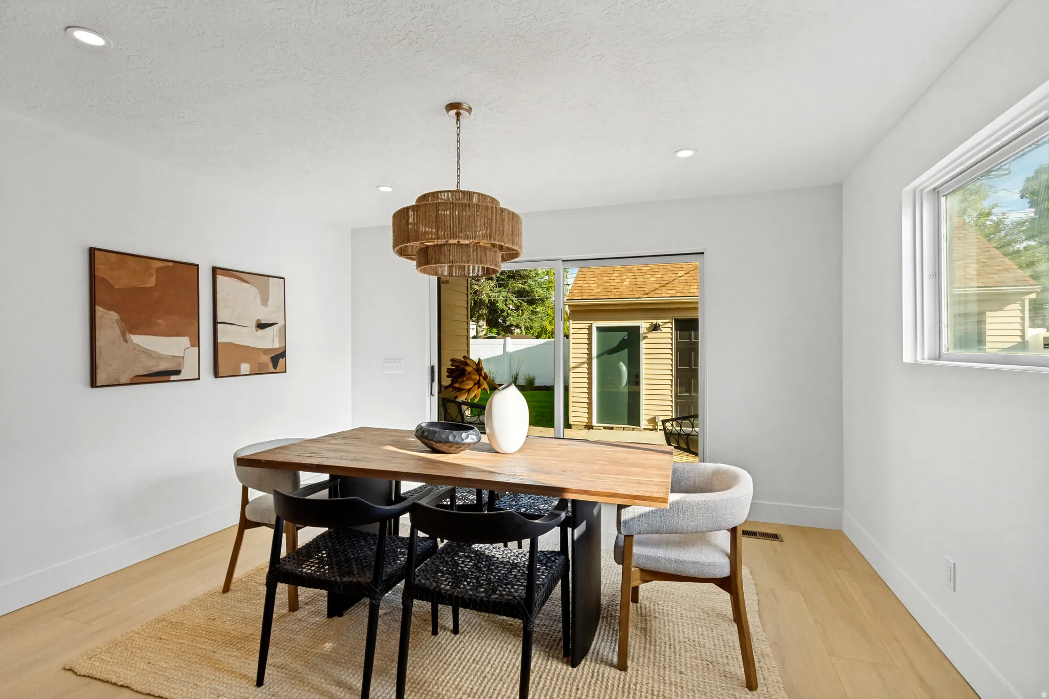 Recessed lighting, wood-finish flooring, sliding glass door, single hung window, and a woven chandelier