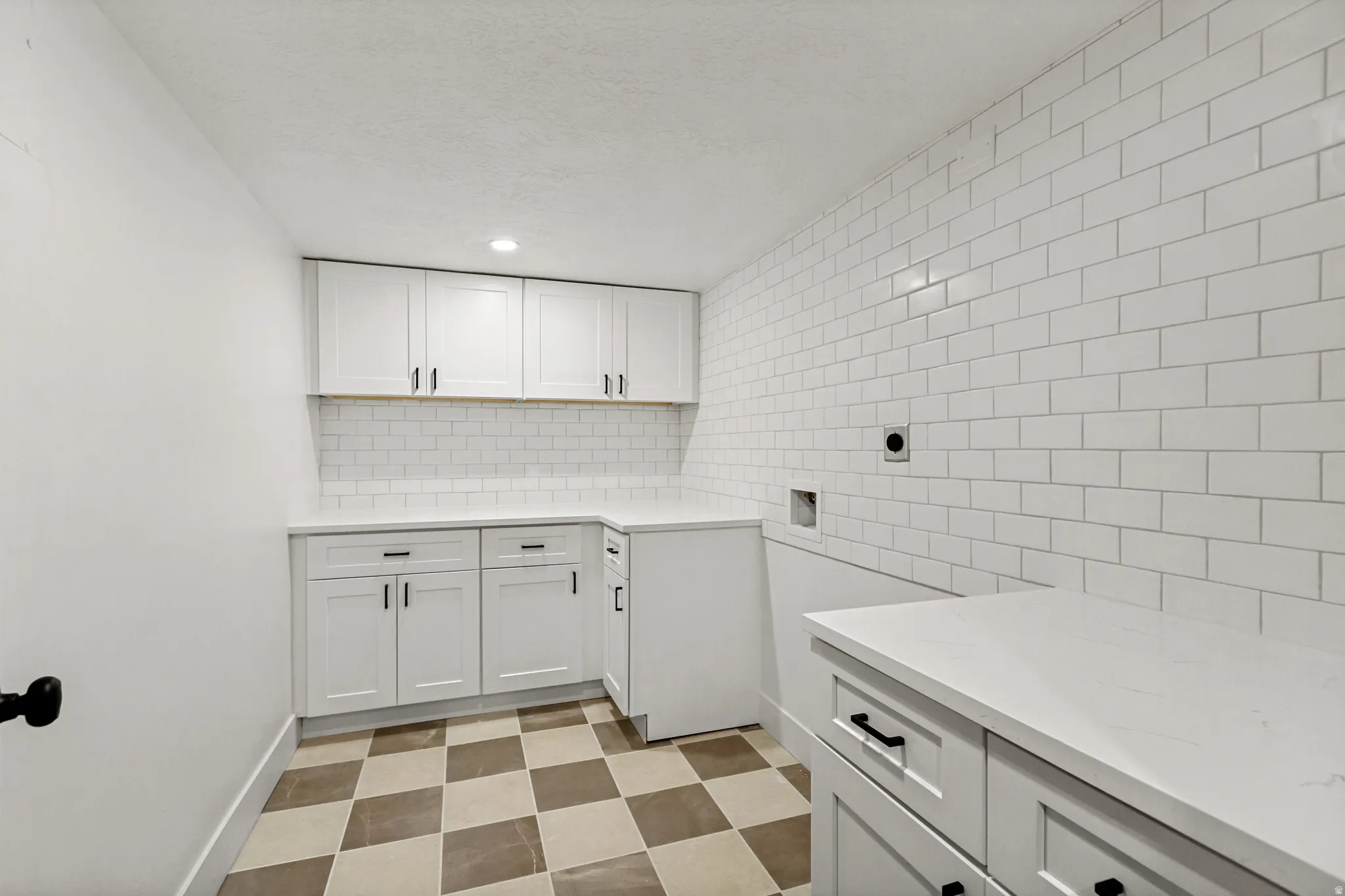 White shaker cabinetry, subway tile backsplash, recessed lighting, checkerboard floor tiling, and solid surface countertops