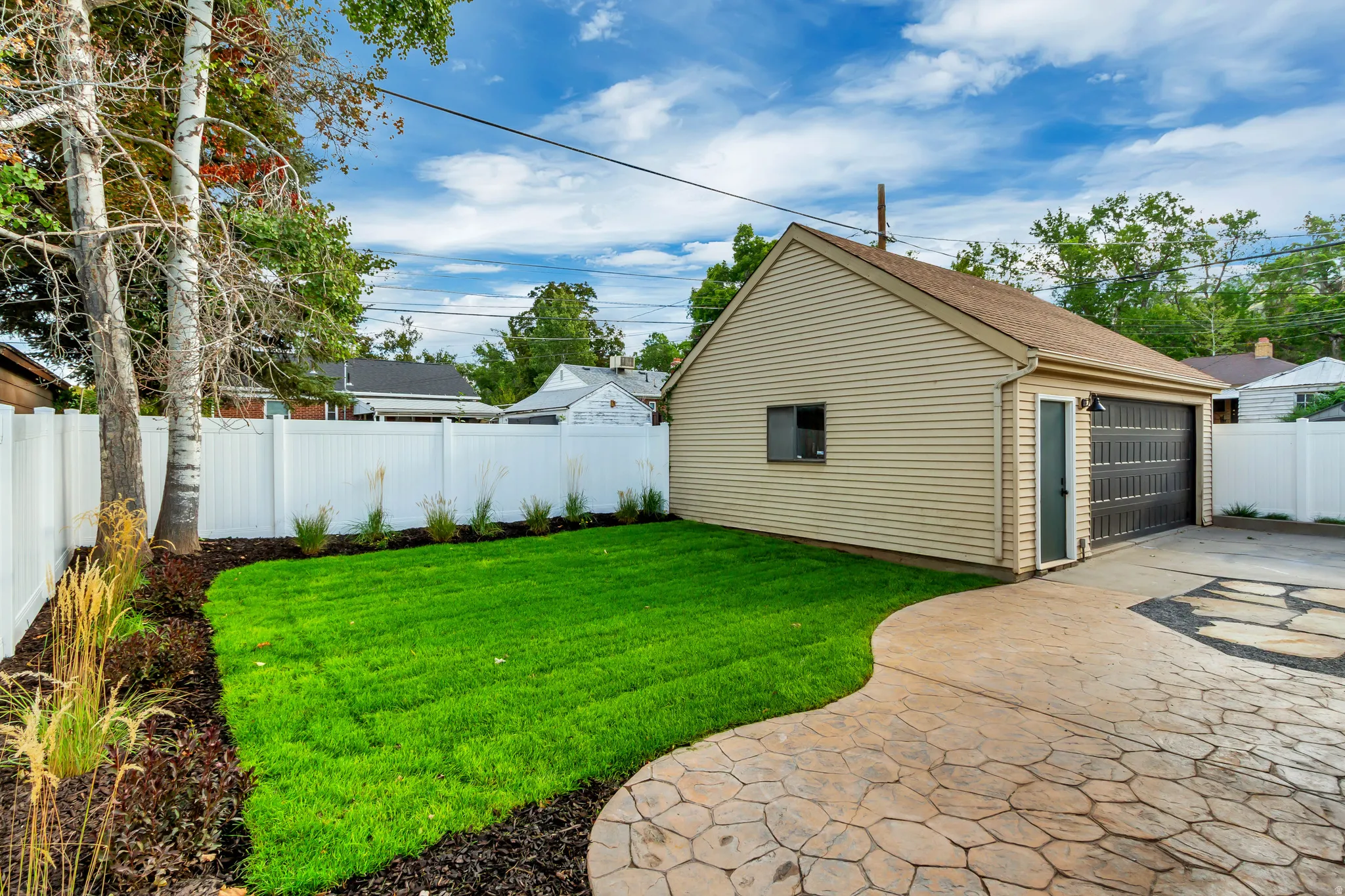 Detached garage with horizontal siding, a single-car garage door, and a separate entry door