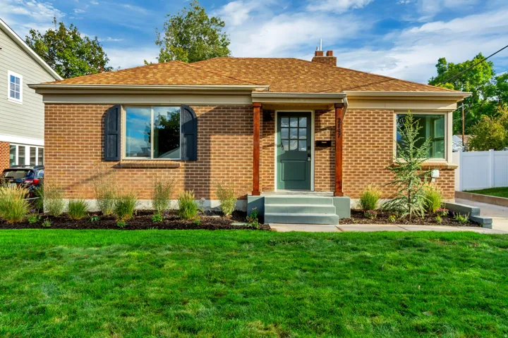 Brick exterior with a peaked roof, arched window shutters, and a wooden porch column