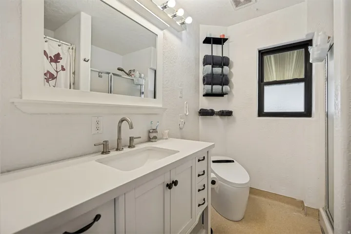 White vanity with black hardware, rectangular undermount sink, and brushed nickel faucet